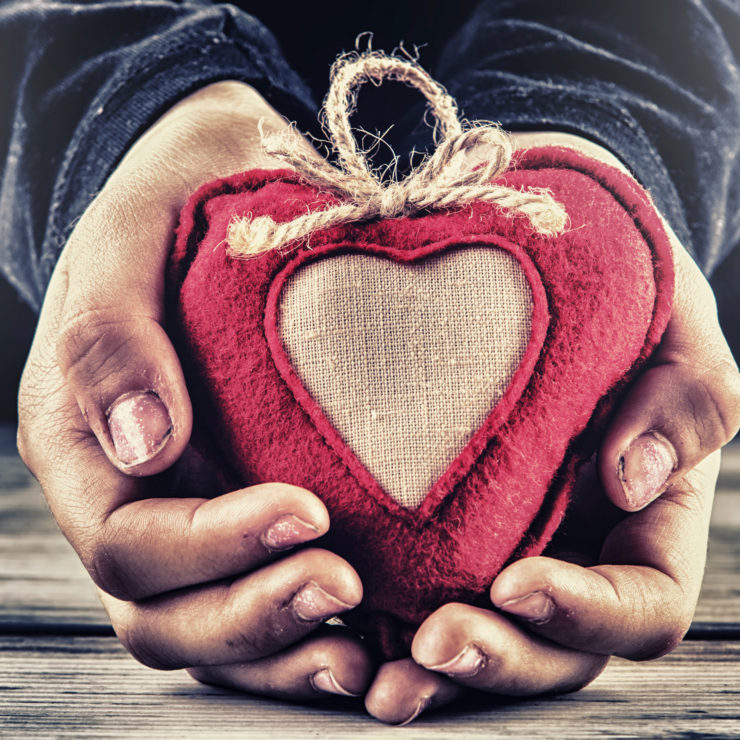 Photo of hands holding a red knitted heart to show that virtues are a necessary step for cultivating well-being