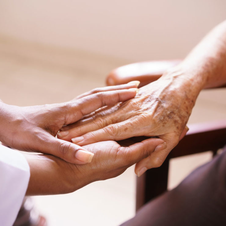 African American Doctor Holding The Hands Of An Elderly Person To Demonstrate End Of Life Care