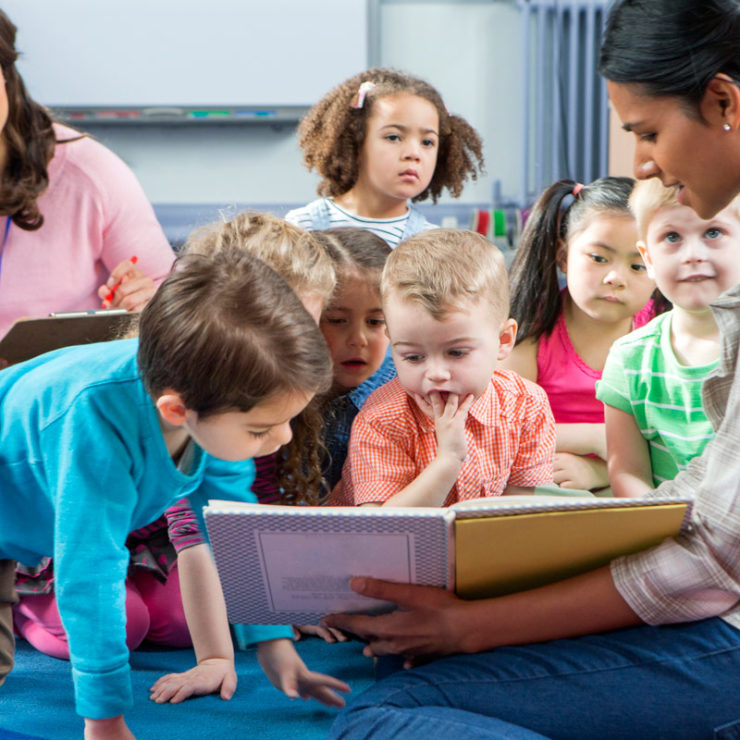 Children gathered around a teacher reading a book. This image demonstrates how teachers can incorporate the Center's Kindness Curriculum into their classrooms.