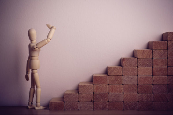 Wooden Figure Contemplating Climbing Stairs