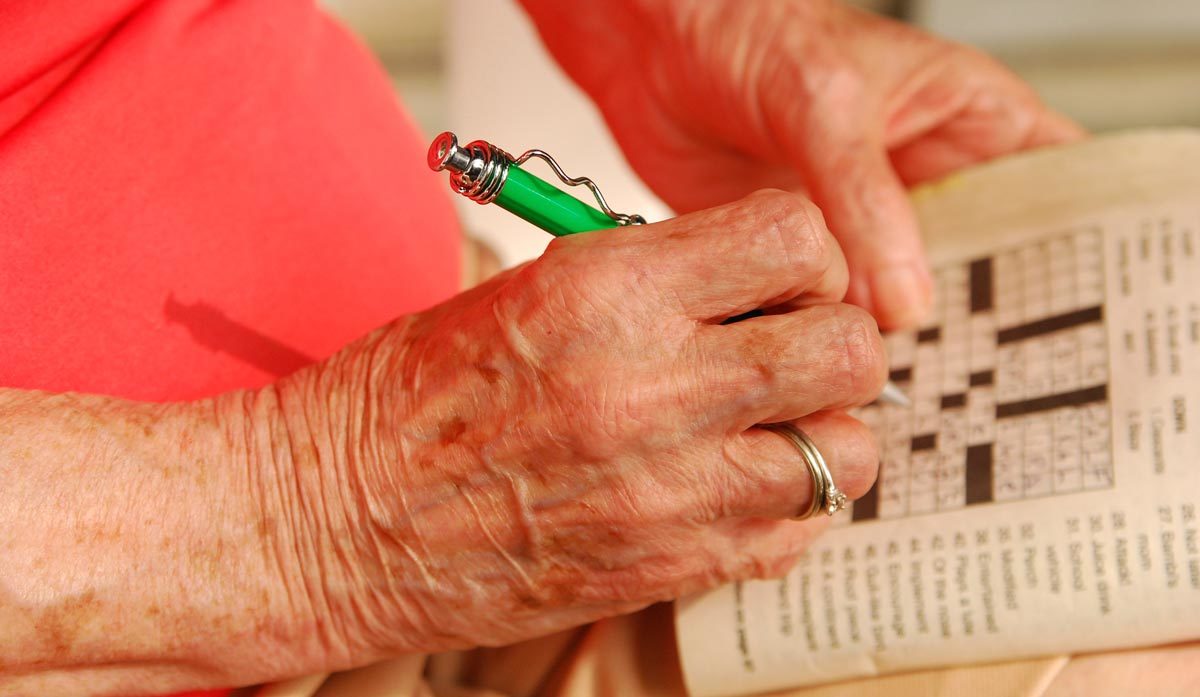 Woman doing crossword puzzle by plamensart via iStock